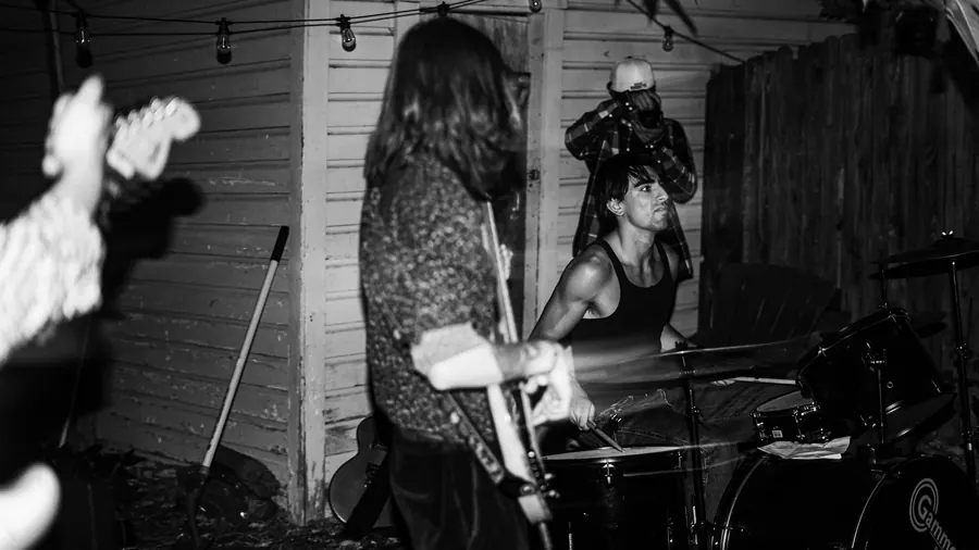 Lady Preacher playing guitar and drums, black and white
