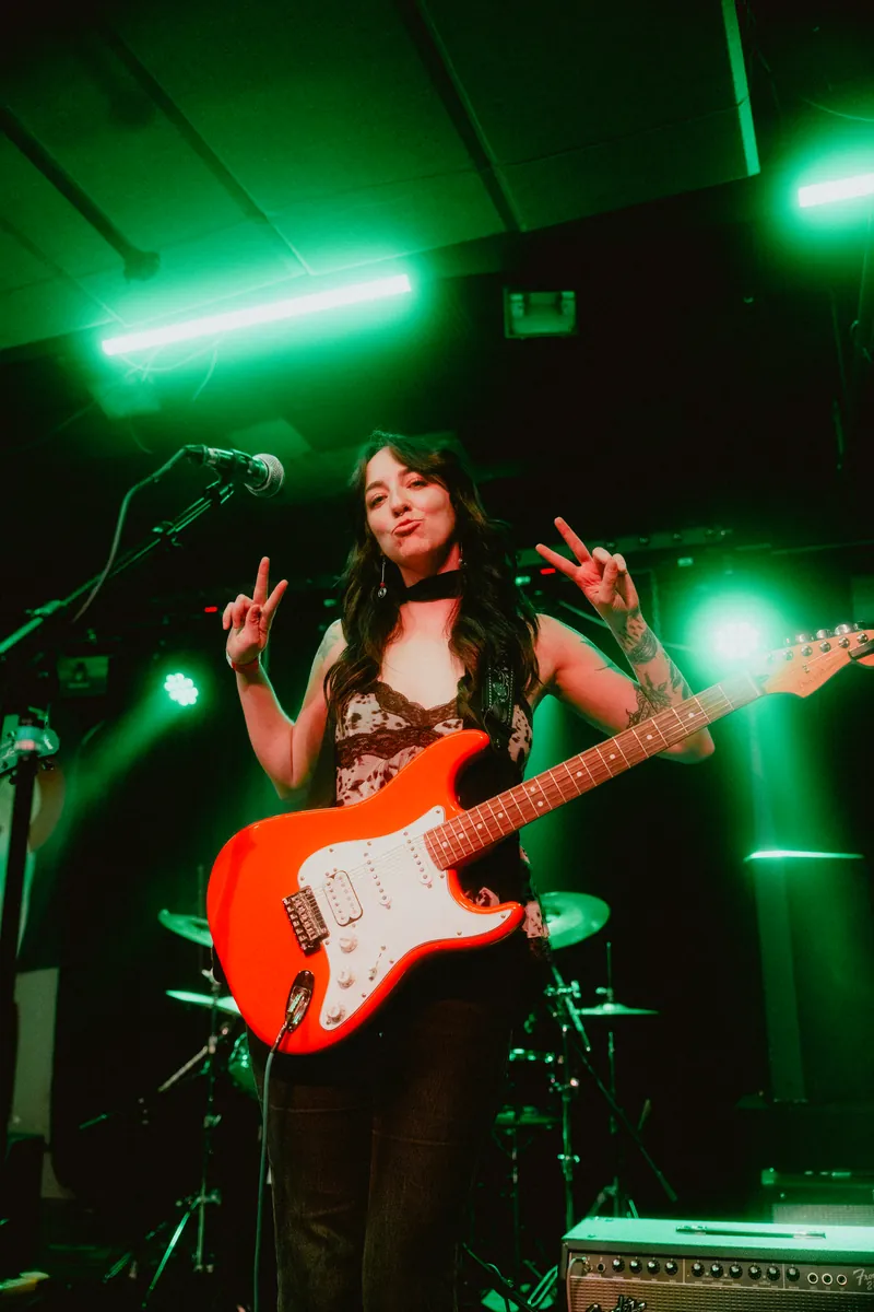 Lilah throwing peace signs with her red Strat