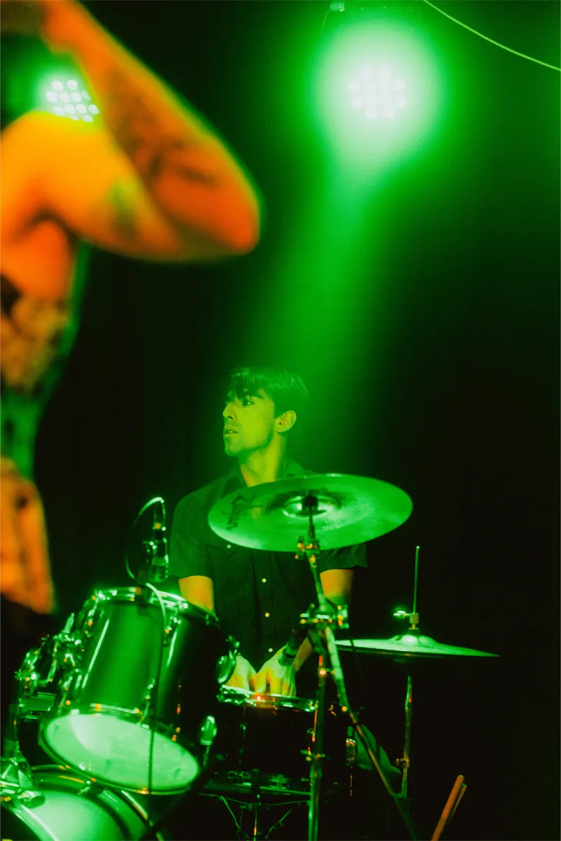 Mateo on drums under green light