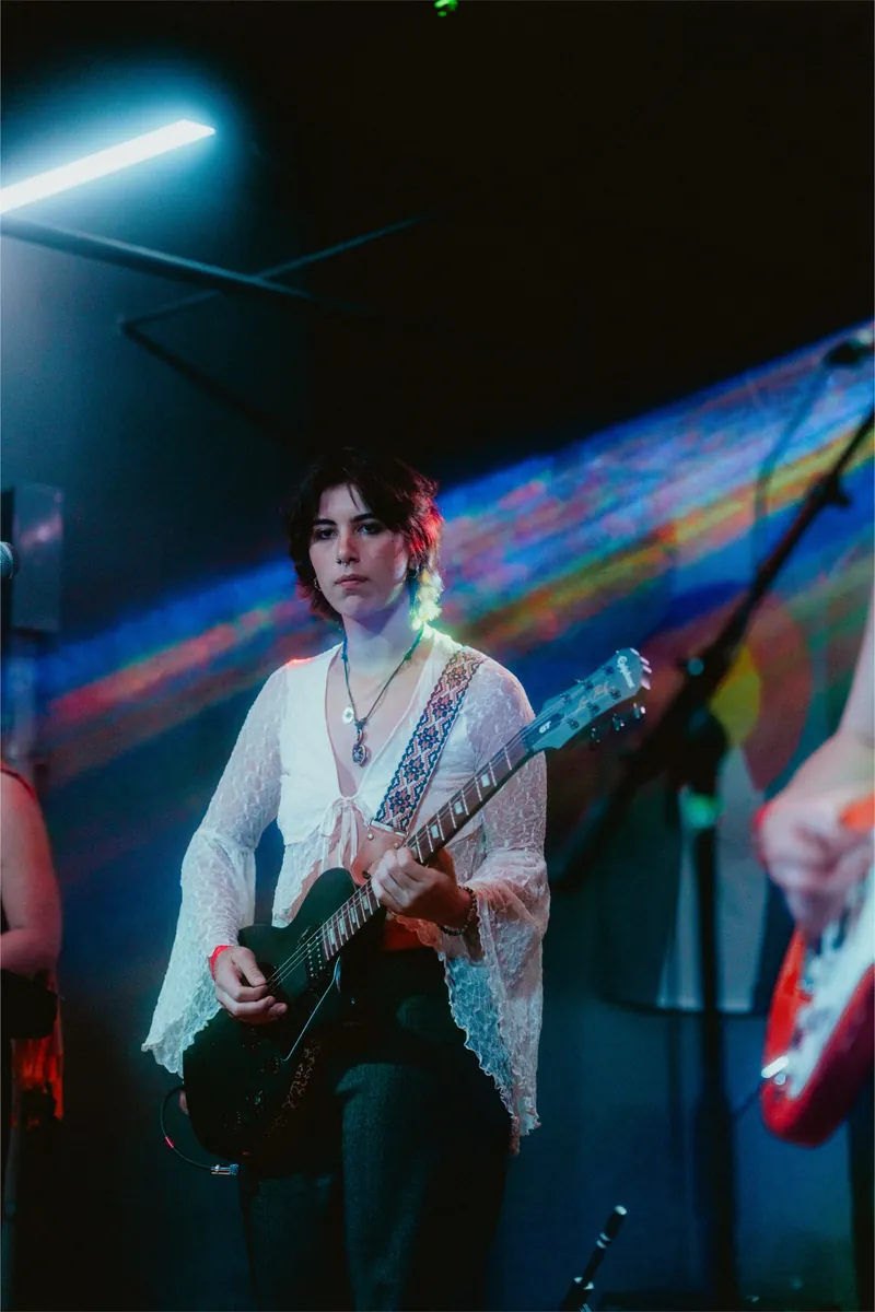 Gavriella in blue light, rainbow flare behind her
